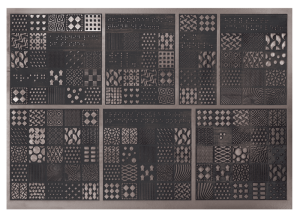 Description: A tactile board of different patterned raised shapes on metallic plating in a grid formation, like a tactile quilt pattern in dark black and grays.