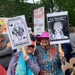 two older women holding the discard and lady justice posters as signs